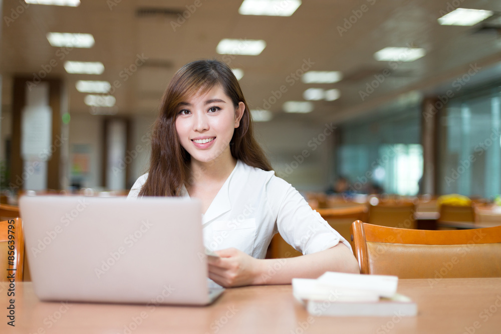 Asian beautiful female student study in library with laptop Asian beautiful female student study in library with laptop