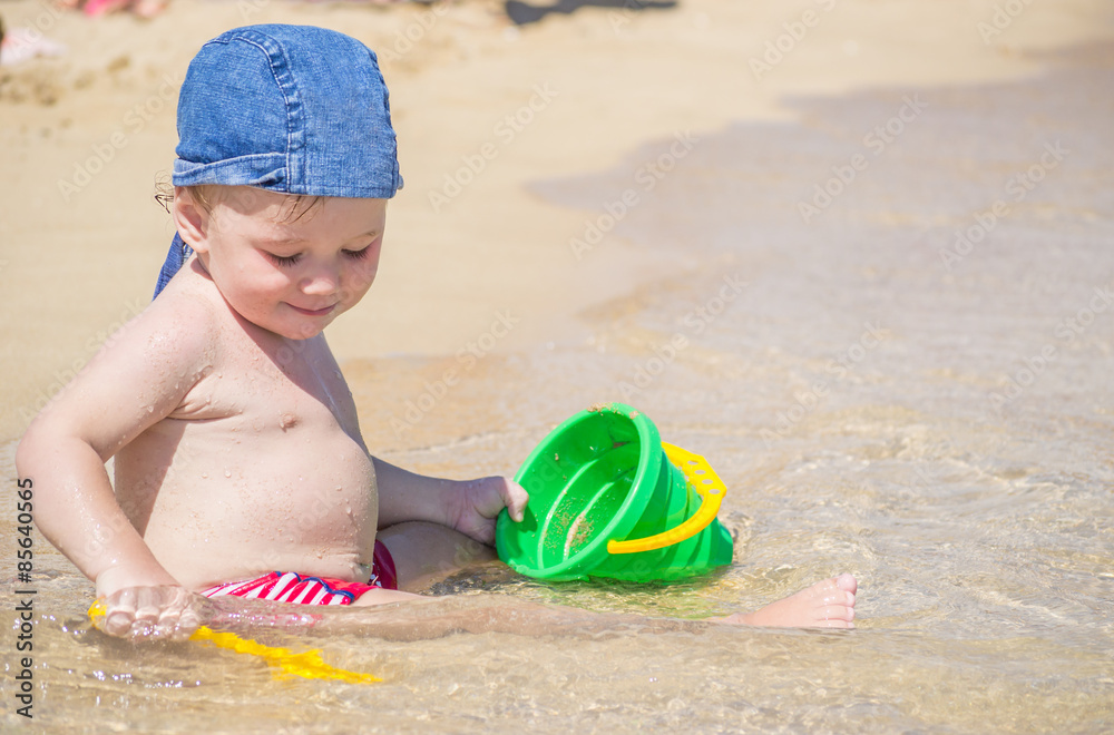 Cute kid playing on the beach with sand and water Cute kid playing on the beach with sand and water
