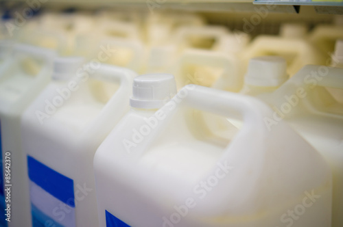 Rows of large milk bottles in fridge in supermarket