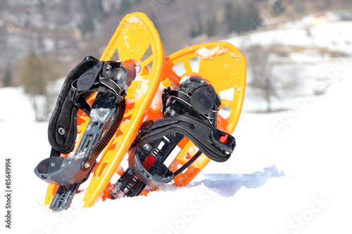 Obraz na plátně two orange snowshoes in mountains in winter