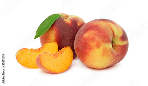 Two whole peaches with green leaf and slices (isolated)
