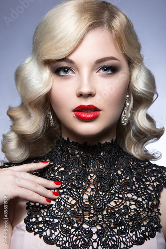 Beautiful blonde in a Hollywood manner with curls, red lips and lace dress. Beauty face. Picture taken in the studio on a white background.