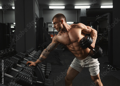 Strong bodybuilder doing exercise with dumbbell © IEGOR LIASHENKO