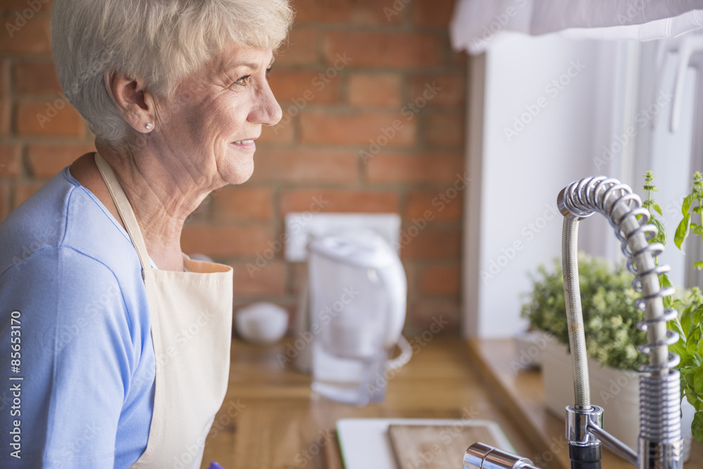 Senior woman looking through the kitchen window