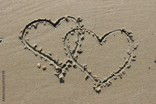 Zwei miteinander verbundene Herzen in den Sand gezeichnet