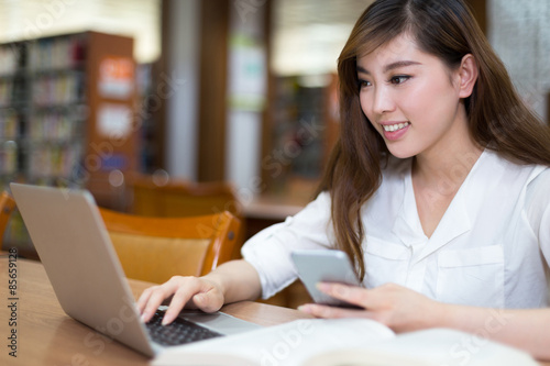 Asian beautiful female student study in library with laptop