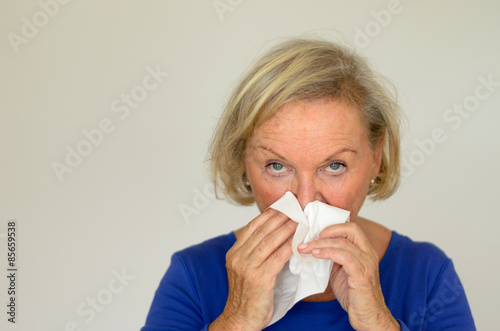 Ältere Frau putzt sich die Nase