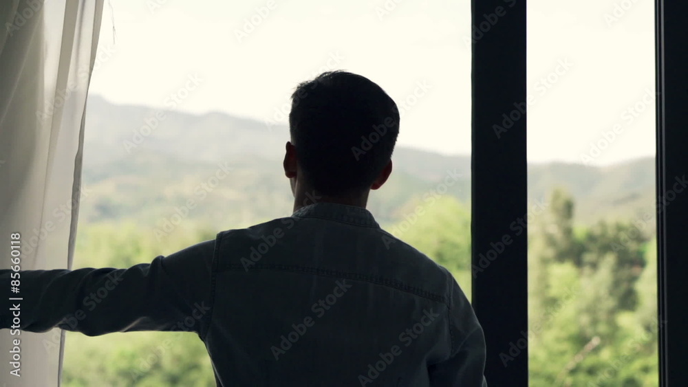 Man unveil curtain, opening door and stretching his arms
