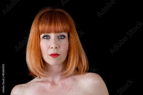 woman with bright red hair naked shoulders isolated on black background