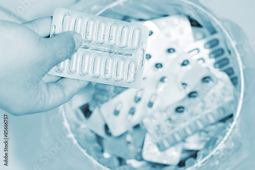 Medikament wird in den Müll entsorgt ,Focus Hand mit Tabletten in leicht blau . 