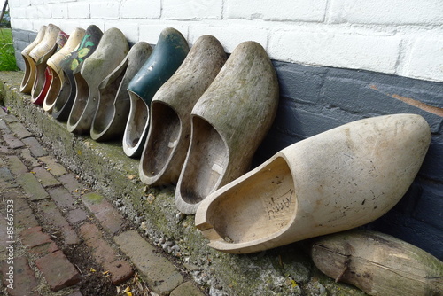 Obraz na plátně An image of clogs in a wall as flowerpots against wall