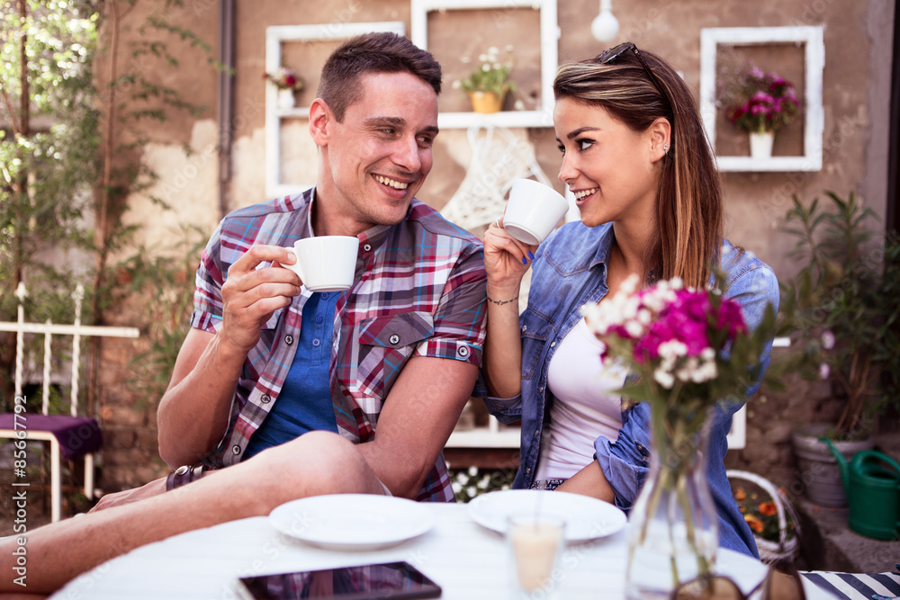 Young happy couple sitting at cafe and drinking coffee 