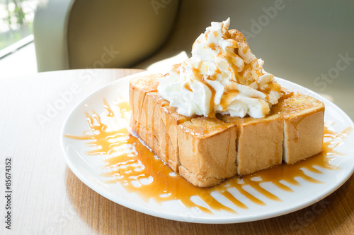 Golden honey toast in the white dish with whipped cream on top