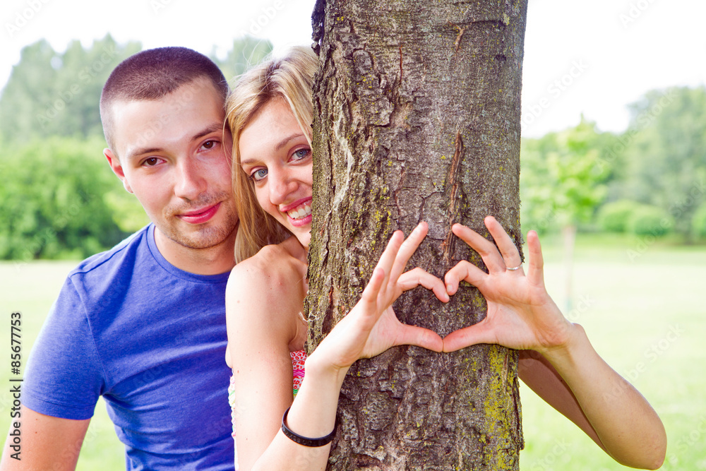 Couple is putting their hands on tree in a shape of heart