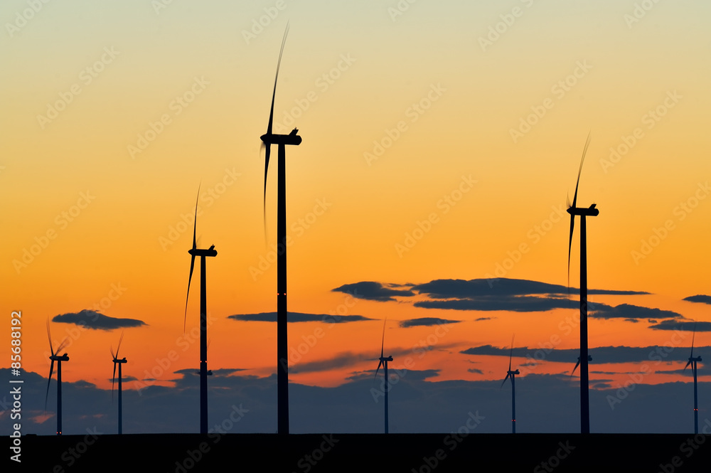 Obraz premium Wind turbine farm with rays of light at sunset
