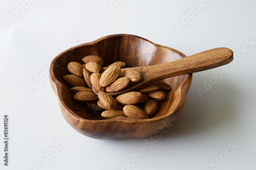Almonds in wooden bowl on white
