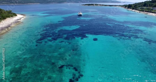 Un catamarán en el medio de una bahía. En la costa Dálmata. Croacia. Agua Transparente, costa rocosa. Paisaje bonito.