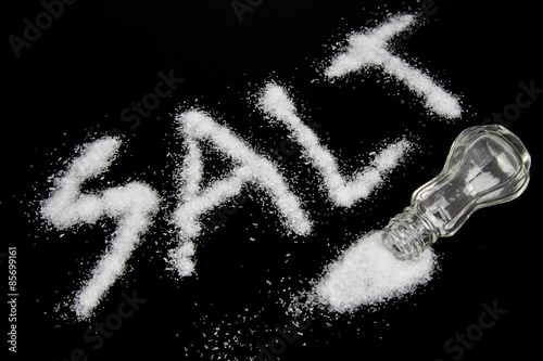 Salt spilled on a table and the word salt written out with the grains of the spice