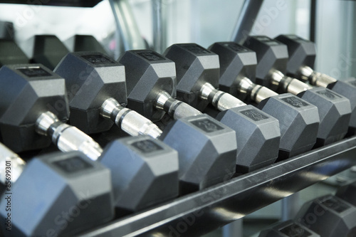 Free weights lined up on rack in fitness gym
