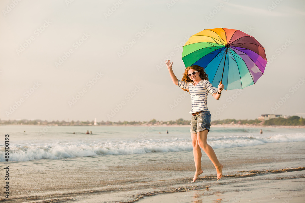 Cheerful young girl with rainbow umbrella having fun on the