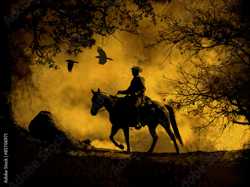 Fototapeta Naklejka Na Ścianę i Meble -  A dramatic design of a cowboy and his horse riding in a meadow into the sunset with crows flying above.  A mixed media piece of artwork in photography and watercolor.