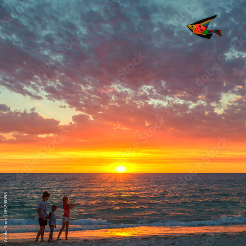 Three children flying a kite on beach at sunset, Hillarys, Joondalup, Australia photo
