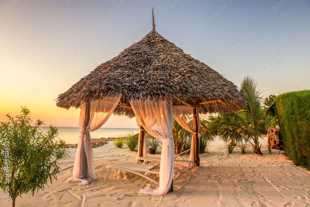 Fototapeta premium Beach lounge chairs at sunset, Zanzibar, Tanzania