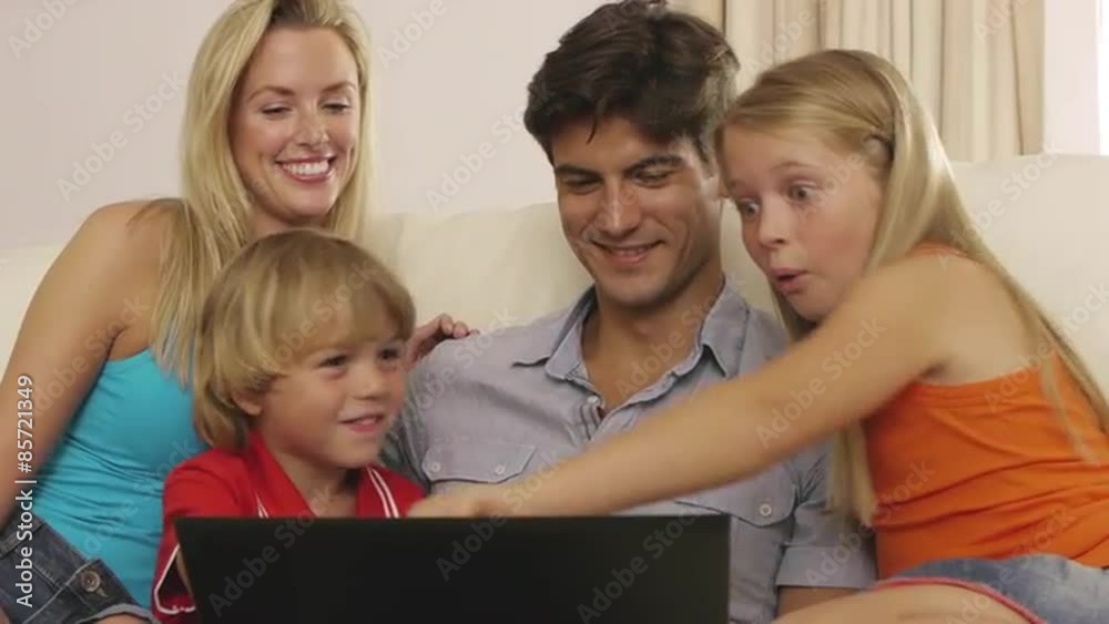 Family on sofa looking at laptop computer. Family on sofa looking at laptop computer.