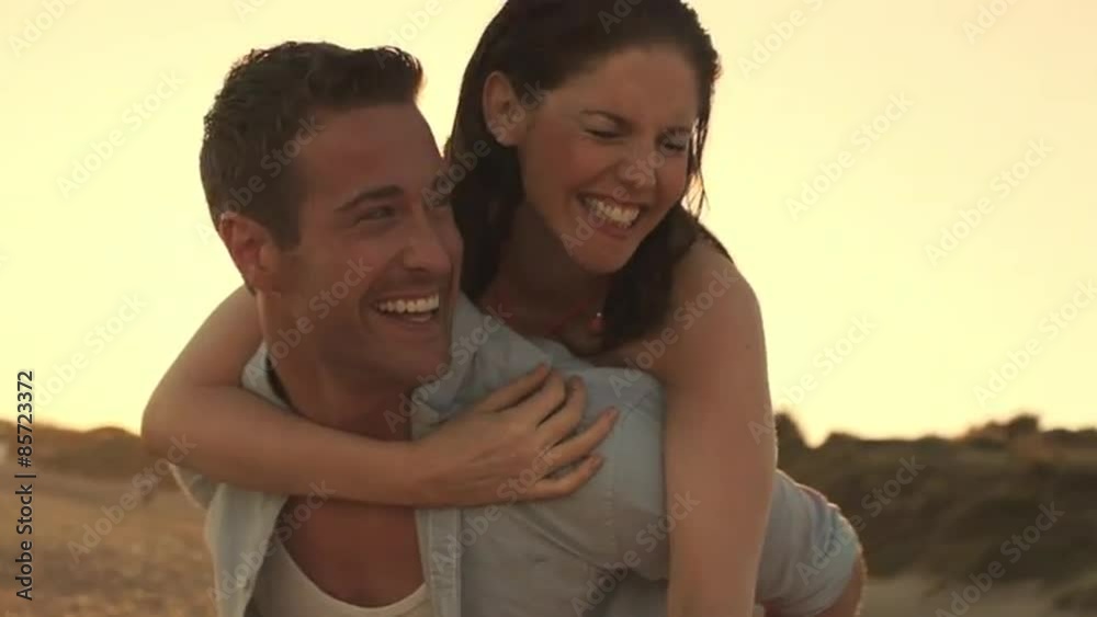 Young couple playing on beach in sunset, man carrying woman on his back. Young couple playing on beach in sunset, man carrying woman on his back.