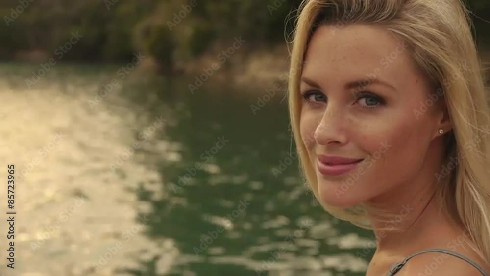 Blond woman's face as she sits beside water. Blond woman's face as she sits beside water.