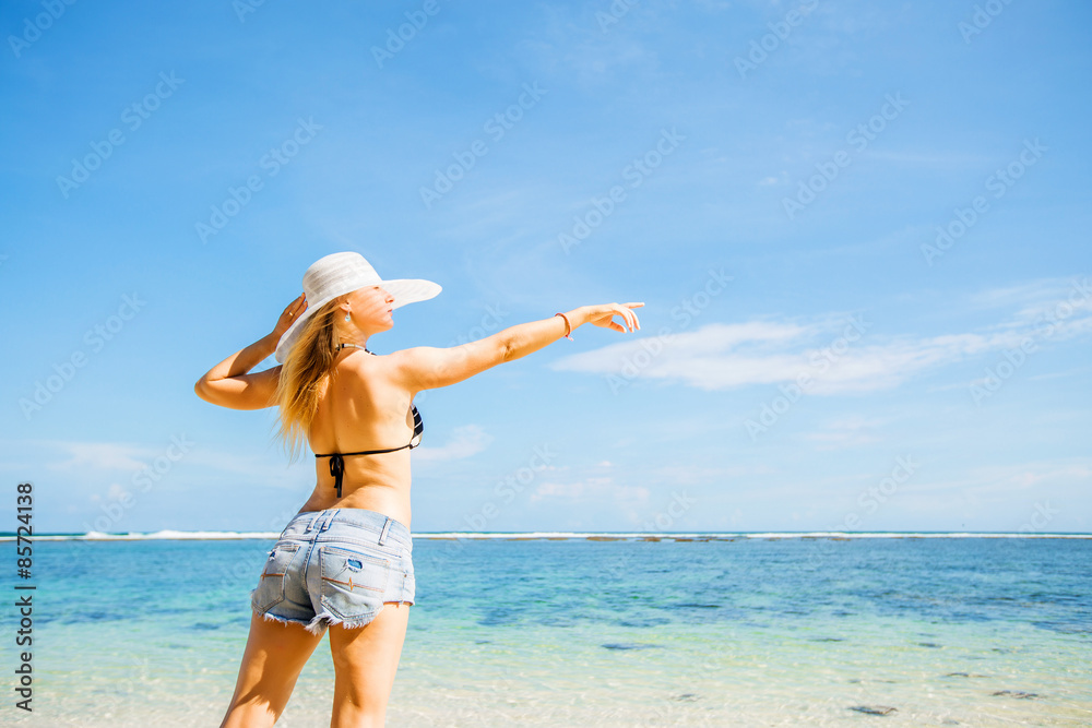 Skinny caucasian tanned woman stays on the rock against blue sky Skinny caucasian tanned woman stays on the rock against blue sky