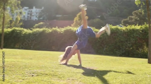 Slow motion of one child doing cartwheels in park.