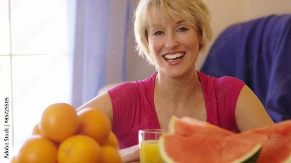 Dolly shot of woman with fruit in foreground holding glass of orange juice. Dolly shot of woman with fruit in foreground holding glass of orange juice.