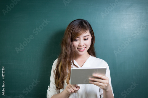 asian beautiful woman holding tablet in front of blackboard