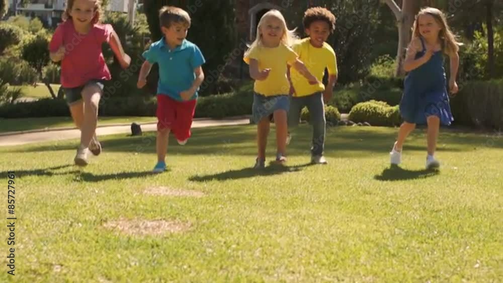 Tilt up slow motion shot of five children running towards camera in park. Tilt up slow motion shot of five children running towards camera in park.