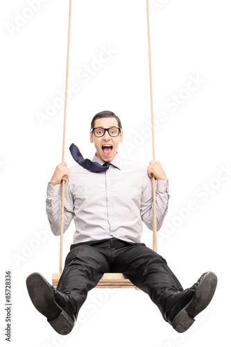 Joyful young guy swinging fast on a swing