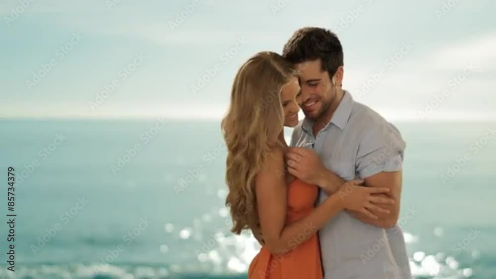 dolly shot of young couple hugging and twirling on beach dolly shot of young couple hugging and twirling on beach
