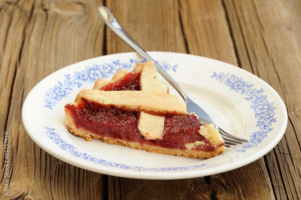 Piece of lattice flan with strawberry jam cut with metal fork on Piece of lattice flan with strawberry jam cut with metal fork on