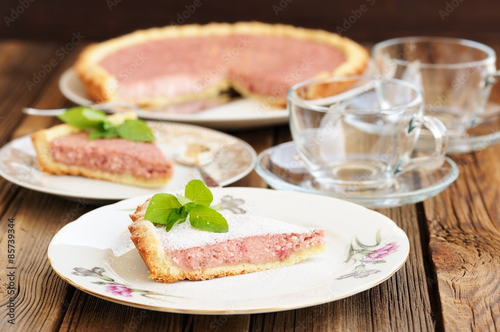 Strawberry tart with two cut pieces decorated with fresh mint an