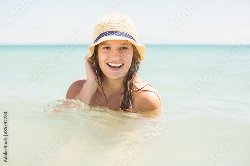 Happy pretty blonde bathing into the sea with hat 