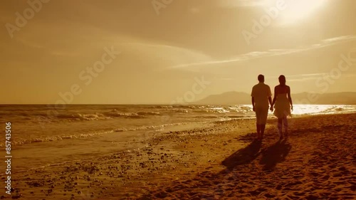 young couple walking on beach in sunset