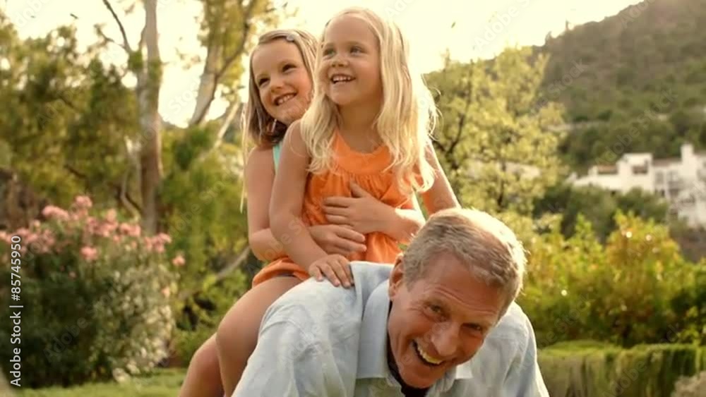 Grandfather carrying two granddaughters on his back in park. Grandfather carrying two granddaughters on his back in park.