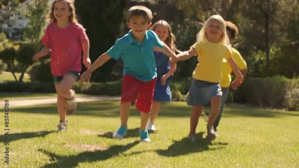 Tilt up slow motion shot of five children running towards camera in park. Tilt up slow motion shot of five children running towards camera in park.