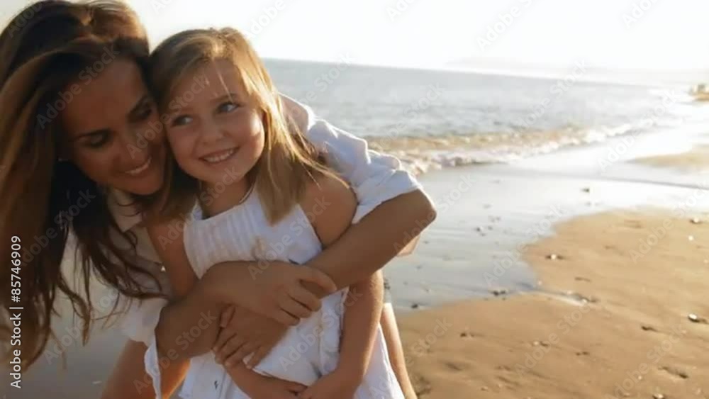 mother cuddling daughter on beach mother cuddling daughter on beach