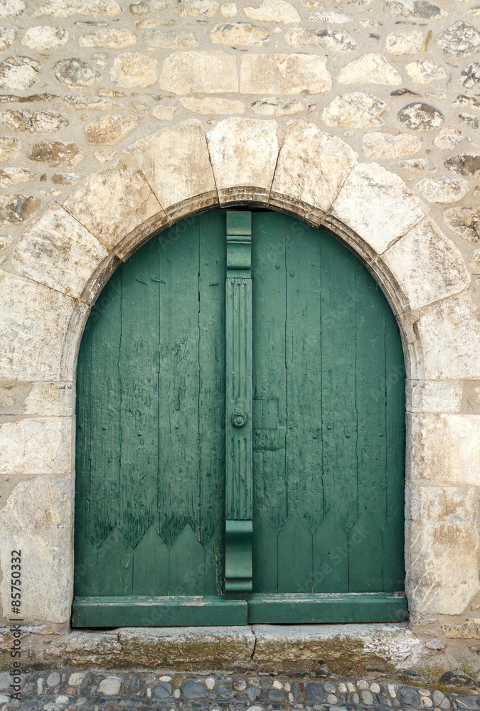 Puerta verde en arco de casa de piedra antigua