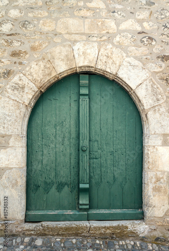 Puerta verde en arco de casa de piedra antigua © dinax