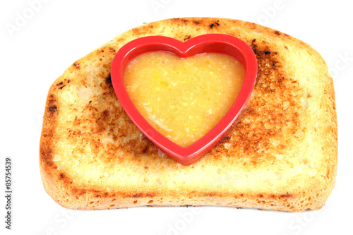 isolated toast with heart shape form filled with orange jam