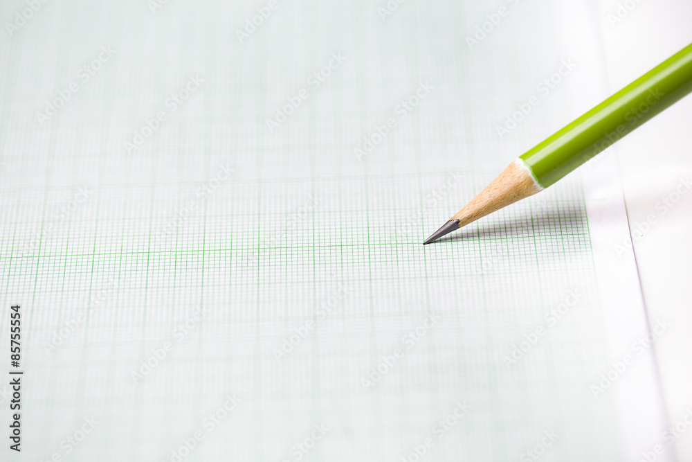 close-up green pencil on graph paper background close-up green pencil on graph paper background