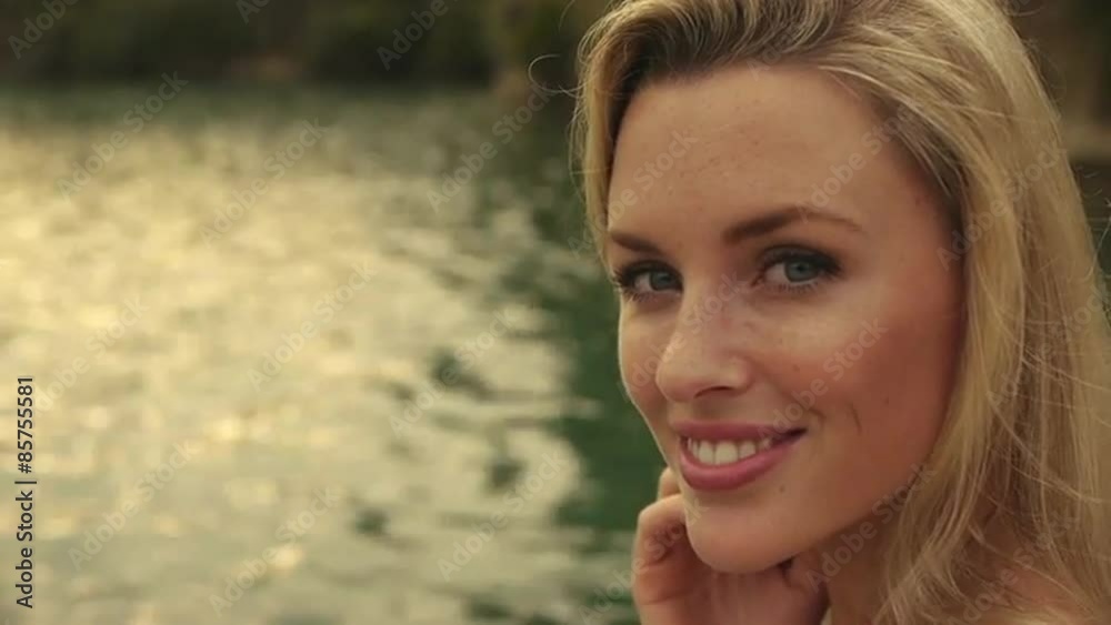 Blond woman's face as she sits beside water. Blond woman's face as she sits beside water.