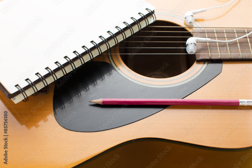 Fototapeta premium Notebook and pencil on guitar